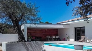 A modern house with a swimming pool, a covered patio, and a wooden deck. - Near Uzès, holiday air-conditioned villa located Vers-Pont-du-Gard, private pool. (VERS-PONT-DU-GARD)