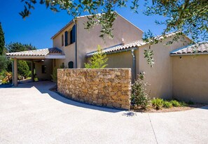 Set amidst lush gardens, this two-story residence features a covered patio with a pergola.