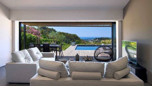 A modern living room with a large window, a pool, and outdoor furniture. - Exceptional air-conditioned house, swimming pool in Ollioules, Var, near Sanary-sur-Mer. (OLLIOULES)