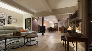 A living room with a sofa, coffee table, and a fireplace. There is a dining area with a table and chairs. - Superb air-conditioned farmhouse with private pool, in Saint-Rémy-de-Provence. (SAINT-REMY-DE-PROVENCE)
