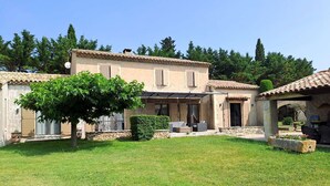 A two-story house with a patio area, a covered seating area, and a stone wall. - Superb air-conditioned farmhouse with private pool, in Saint-Rémy-de-Provence. (SAINT-REMY-DE-PROVENCE)
