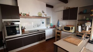 A modern kitchen with a built-in oven, microwave, and sink. There are cabinets, a wooden countertop, and various kitchen utensils. - 0.1 ml from the beach, house with large terrace and beautiful sea view. (CARRY-LE-ROUET)