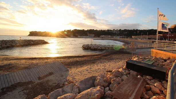 A beach with a wooden walkway, rocky shore, and a flag. - 0.1 ml from the beach, house with large terrace and beautiful sea view. (CARRY-LE-ROUET)
