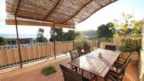 A covered patio with a table and chairs, overlooking a scenic view of the sea and trees. - 0.1 ml from the beach, house with large terrace and beautiful sea view. (CARRY-LE-ROUET)