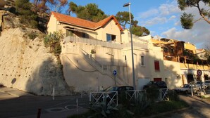 A building with a red-tiled roof, a staircase leading to a balcony, and a parked car in front. - 0.1 ml from the beach, house with large terrace and beautiful sea view. (CARRY-LE-ROUET)