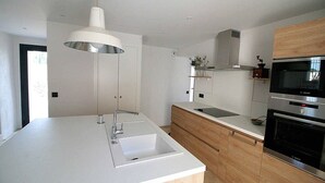 A modern kitchen with a white countertop, stainless steel appliances, and wooden cabinetry. - Holiday rental in Le Castellet, sea and beach 10 km. (LE CASTELLET)