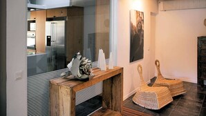 A modern kitchen with a wooden console table, a refrigerator, and a glass partition. There are woven baskets on the floor and a framed picture on the wall. - Air-conditioned villa near Vaison-la-Romaine, with heated pool. (FAUCON)