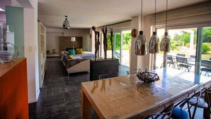 A modern kitchen with a wooden table, hanging pendant lights, and a view to the outside. - Air-conditioned villa near Vaison-la-Romaine, with heated pool. (FAUCON)