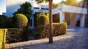 A modern building with a flat roof, surrounded by well-manicured hedges and a gravel driveway. - Air-conditioned villa near Vaison-la-Romaine, with heated pool. (FAUCON)