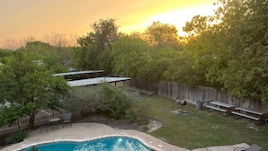 A backyard with a swimming pool, picnic tables, and a wooden fence. - Peaceful river views/Guadalupe access/Swimming Pool/2 bed 2 bath/Sleeps 6 (New Braunfels)