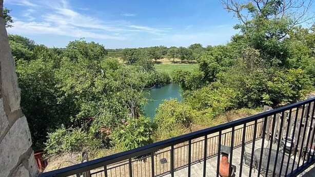 A balcony with a view of a river surrounded by dense greenery. - Peaceful river views/Guadalupe access/Swimming Pool/2 bed 2 bath/Sleeps 6 (New Braunfels)