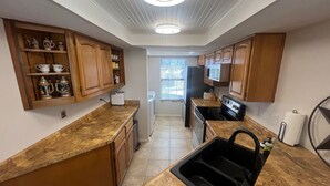 A kitchen with wooden cabinets, a granite countertop, a black sink, and a refrigerator. - Peaceful river views/Guadalupe access/Swimming Pool/2 bed 2 bath/Sleeps 6 (New Braunfels)