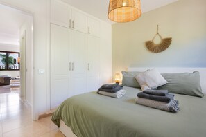 A bedroom with a bed, pillows, a bedside lamp, a wall hanging, and a wardrobe. - Vacation 'Oasis Duna-Pistacho Dreams Pool' with Shared Pool, Private Terrace and Wi-Fi (corralejo)