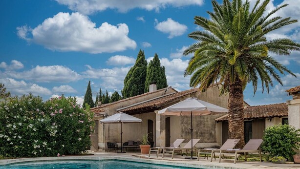 A poolside area with lounge chairs and umbrellas, surrounded by greenery and a clear sky. - Villa for 8P, heated pool, table tennis, boules, in Maillane, Alpilles, pets admitted (1). (MAILLANE)