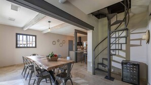 A spacious dining area with a long wooden table and metal chairs, a kitchen in the background, and a spiral staircase. - Villa for 8P, heated pool, table tennis, boules, in Maillane, Alpilles, pets admitted (1). (MAILLANE)