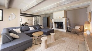 A modern living room with a grey sectional sofa, a round coffee table, and a fireplace. - Villa for 8P, heated pool, table tennis, boules, in Maillane, Alpilles, pets admitted (1). (MAILLANE)