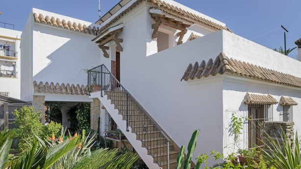 A white building with a tiled roof, a staircase, and a balcony.