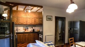 A compact kitchen with wooden cabinets, a dining area with a table and chairs, and a bed with pillows. - Air-conditioned villa in the Luberon countryside, with fenced pool, pets allowed (2). (LIOUX)