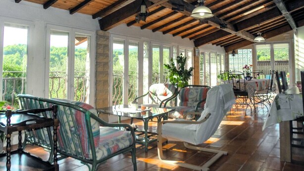 A spacious room with wooden beams, large windows, and a balcony with outdoor furniture. - Air-conditioned villa in the Luberon countryside, with fenced pool, pets allowed (2). (LIOUX)