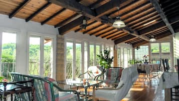 A spacious room with wooden beams, large windows, and a balcony with outdoor furniture.