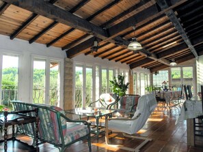 A spacious room with wooden beams, large windows, and a balcony with outdoor furniture. - Air-conditioned villa in the Luberon countryside, with fenced pool, pets allowed (2). (LIOUX)