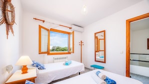 Une chambre d’hôtel avec deux lits, une fenêtre, un miroir, une lampe et un banc.