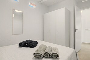 Una habitación de hotel con cama, dos juegos de toallas, un armario y una puerta.