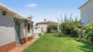 A residential property with a well-maintained lawn, outdoor seating, and a variety of plants.
