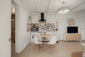 Una cocina compacta con lavadora, microondas y comedor con dos sillas.