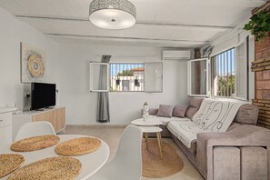 Una sala de estar moderna con un televisor de pantalla plana, un sofá, una mesa de centro y un comedor.