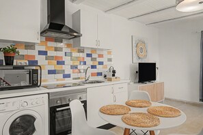 Una cocina moderna con microondas, estufa, pileta y lavadora. Hay individuales tejidos sobre una mesa.