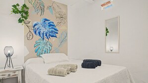 A bedroom with a bed, a wall-mounted mirror, and a decorative wall art piece.