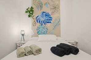 Una habitación de hotel con una cama, dos mesitas de noche, una lámpara y toallas.