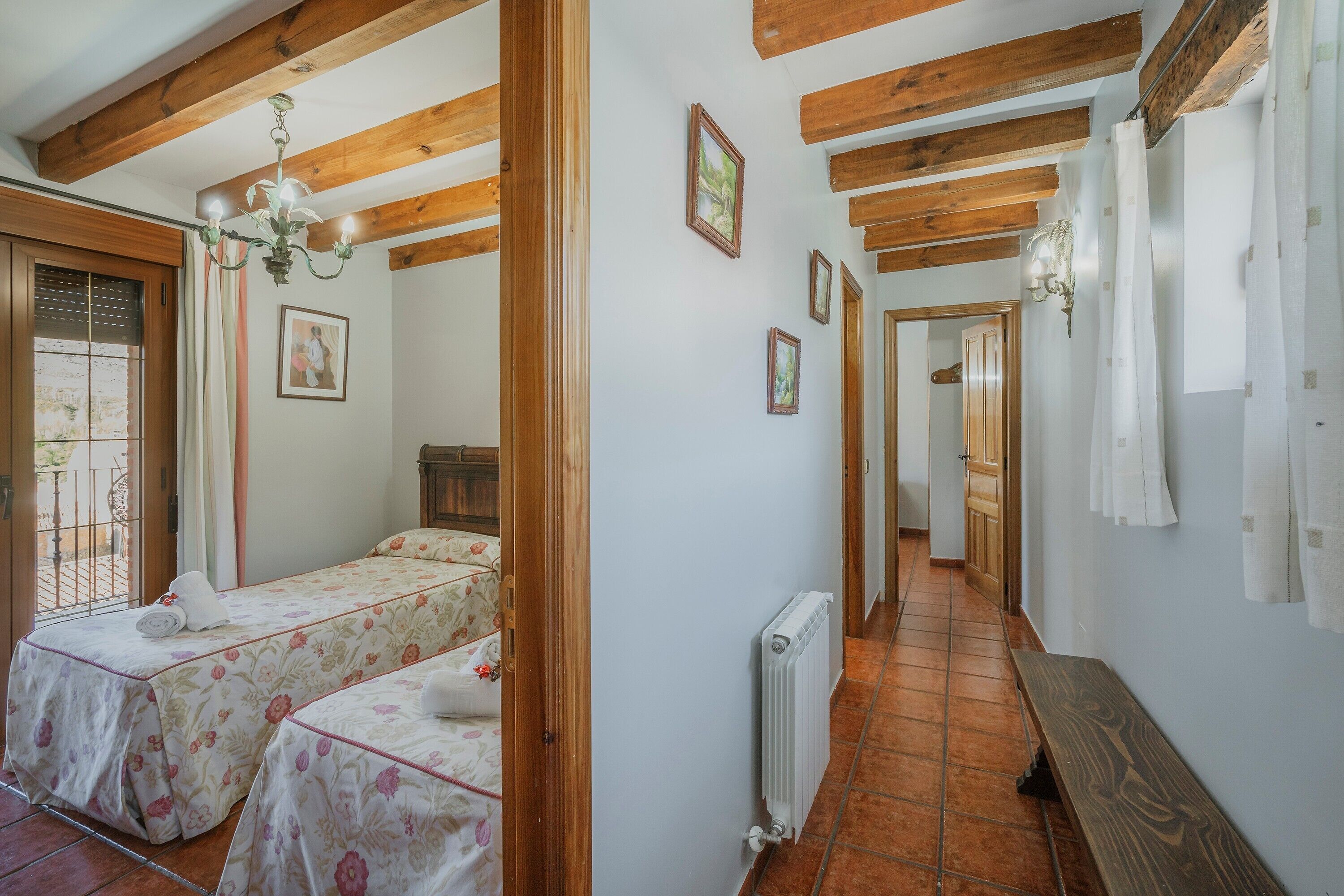 Een kamer met twee bedden, een houten plafond, een radiator en een bank.