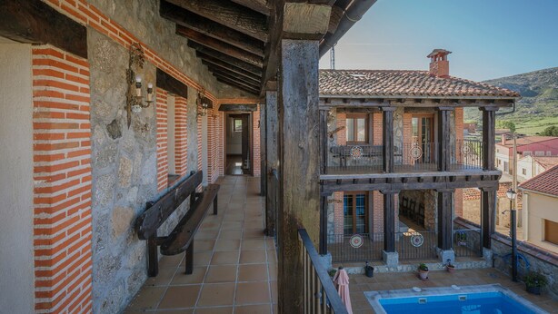 A building with a balcony, a pool, and a view of the surrounding area. - Country House 'Las Eras De Riofrio' with Mountain View, Private Pool and Wi-Fi (Riofrio)