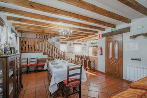 A dining area with wooden beams, a chandelier, and a staircase.