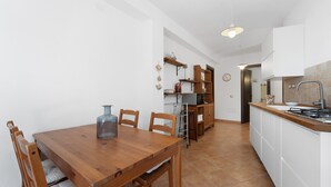 A kitchen with a wooden table and chairs, a stove, and a sink.