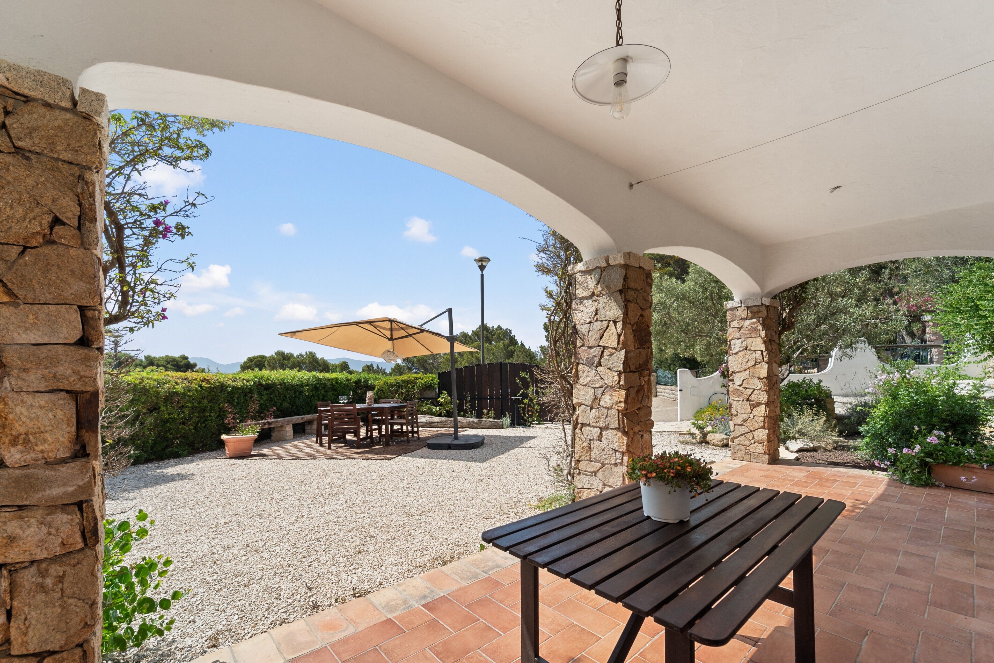 An outdoor patio with a table, chairs, and a potted plant.