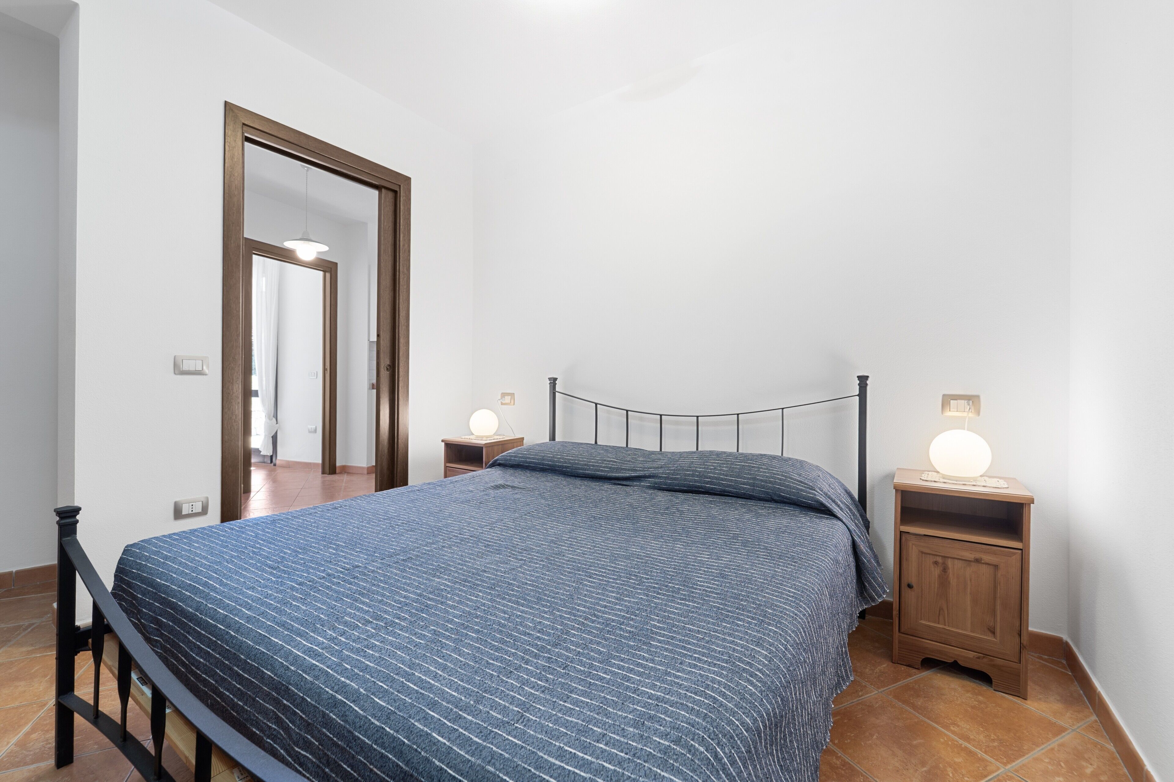 Ein Schlafzimmer mit einem Bett, Nachttischen, einem Spiegel und einer Tür.
