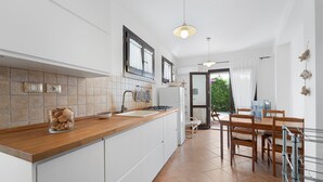 A modern kitchen with a wooden countertop, white cabinets, a sink, and a dining area with a table and chairs.