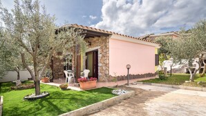 A house with a stone facade, a small patio with a table and chairs, and a well-maintained lawn.