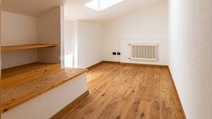 A room with a sloped ceiling, wooden flooring, a radiator, and a skylight. - Apartment 'Preiss Type B' with Mountain View, Balcony and Wi-Fi (Schenna)
