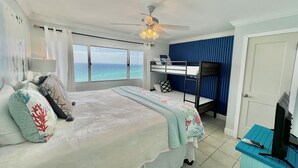 A hotel room with a bed, a desk, a ceiling fan, and a view of the ocean. - Paradise Found On the Beach PH16 (Panama City Beach)