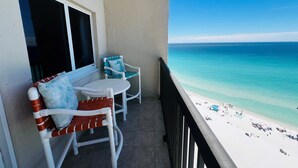 A balcony with a white chair, a small table, and a view of the ocean. - Paradise Found On the Beach PH16 (Panama City Beach)