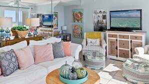 A spacious living room with a white ceiling fan, a large flat-screen TV, and a view of the ocean through a large window. - Paradise Found On the Beach PH16 (Panama City Beach)