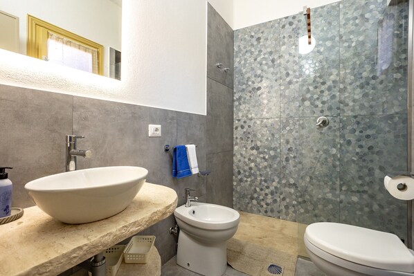 Un baño con un lavabo de pedestal grande, un bidé y un inodoro.