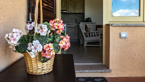A wicker basket with flowers on a table outside a building with a door and a window.
