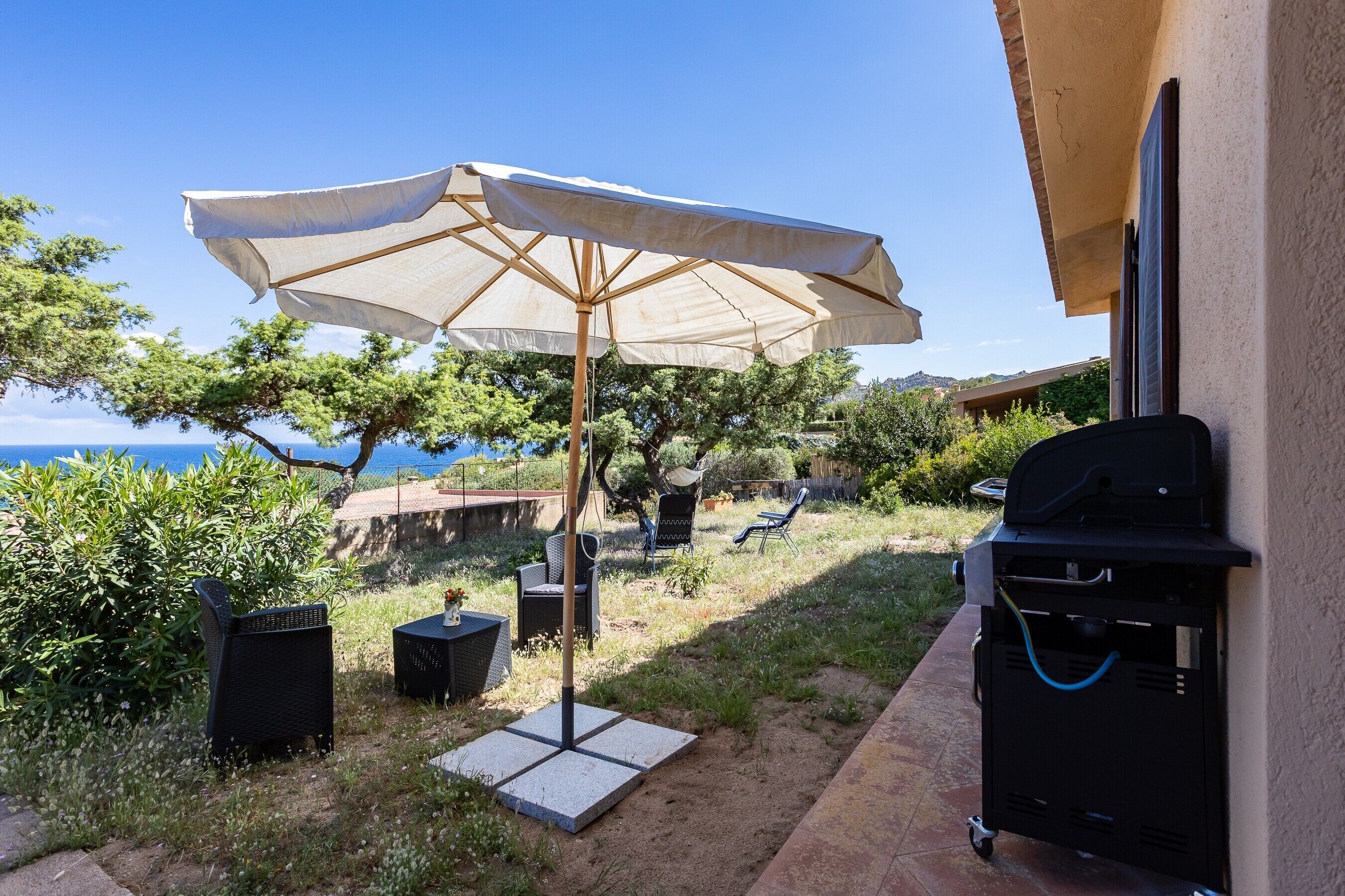 Une terrasse avec un barbecue, du mobilier d’extérieur et une vue sur la mer.