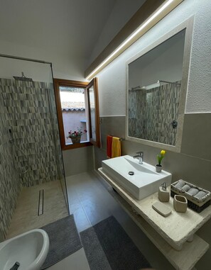 Ein modernes Badezimmer mit einer Duschkabine, einem großen Waschbecken mit Spiegel und einer Badewanne.