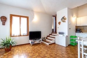 Ein Wohnzimmer mit Fernseher, einer Treppe, einer Küche und einem Essbereich.